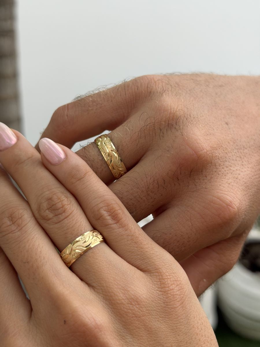 Argollas de matrimonio en oro, una en la mano de ella y otra en la de él